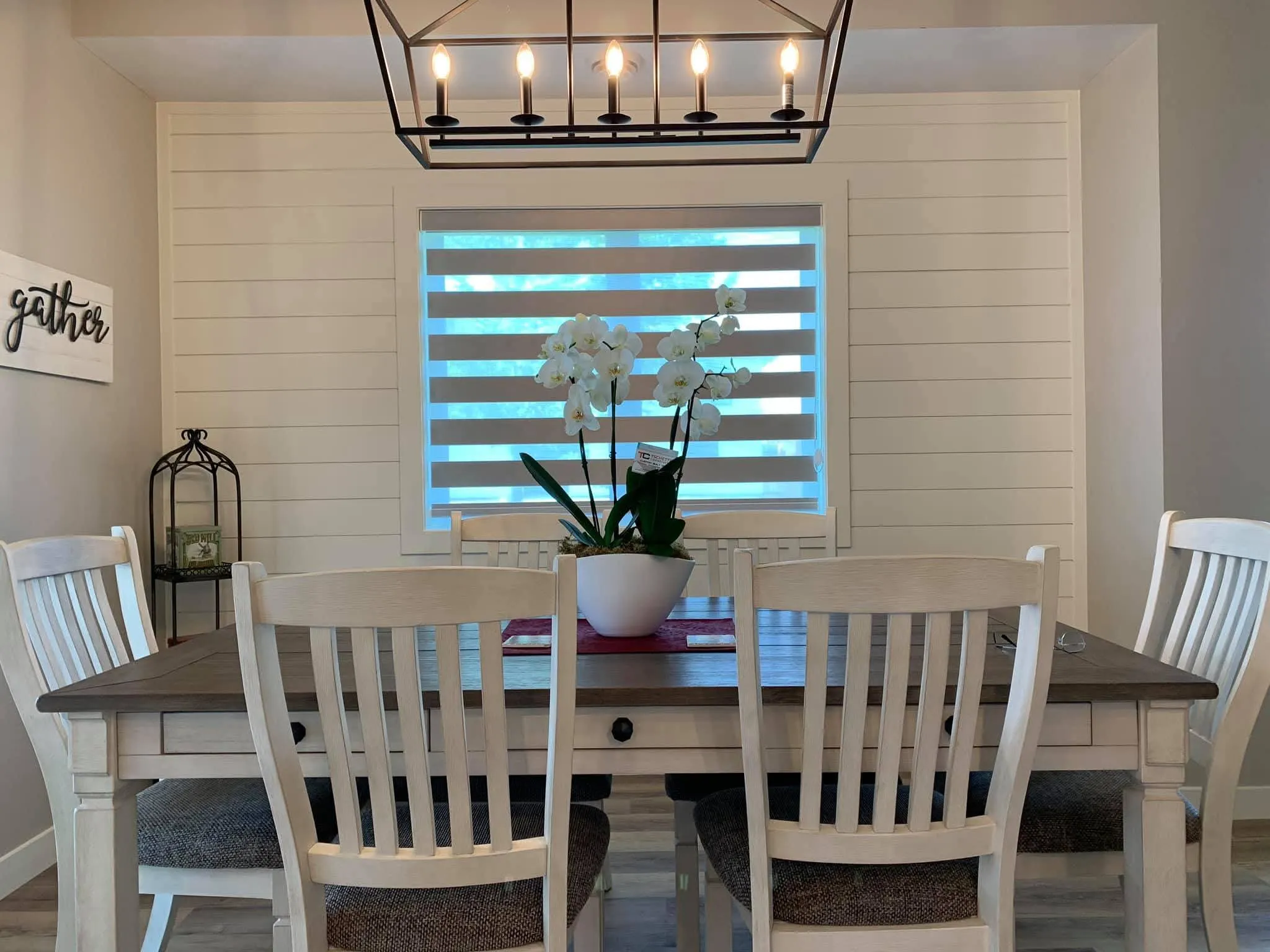 Grey day and night blind on a dining room window behind a farmhouse table
