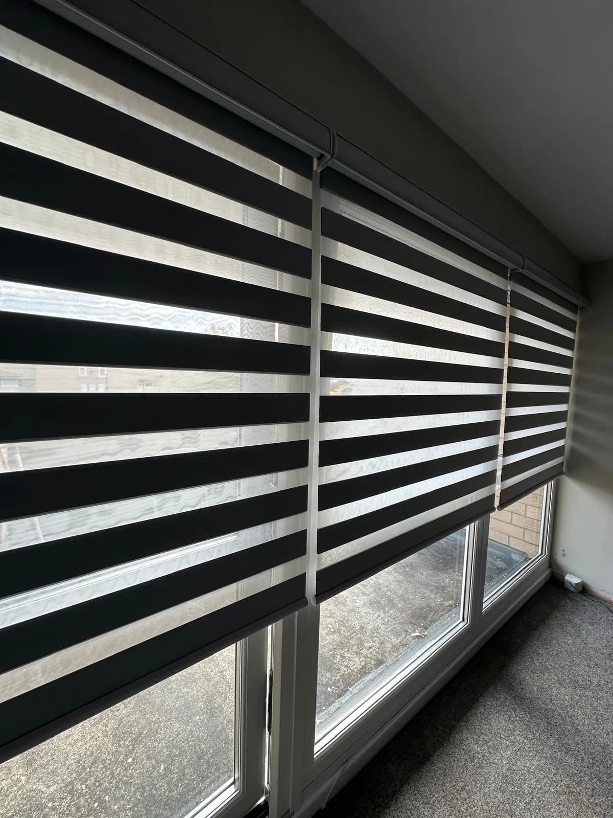 A row of black-and-white day and night blinds across a bank of windows