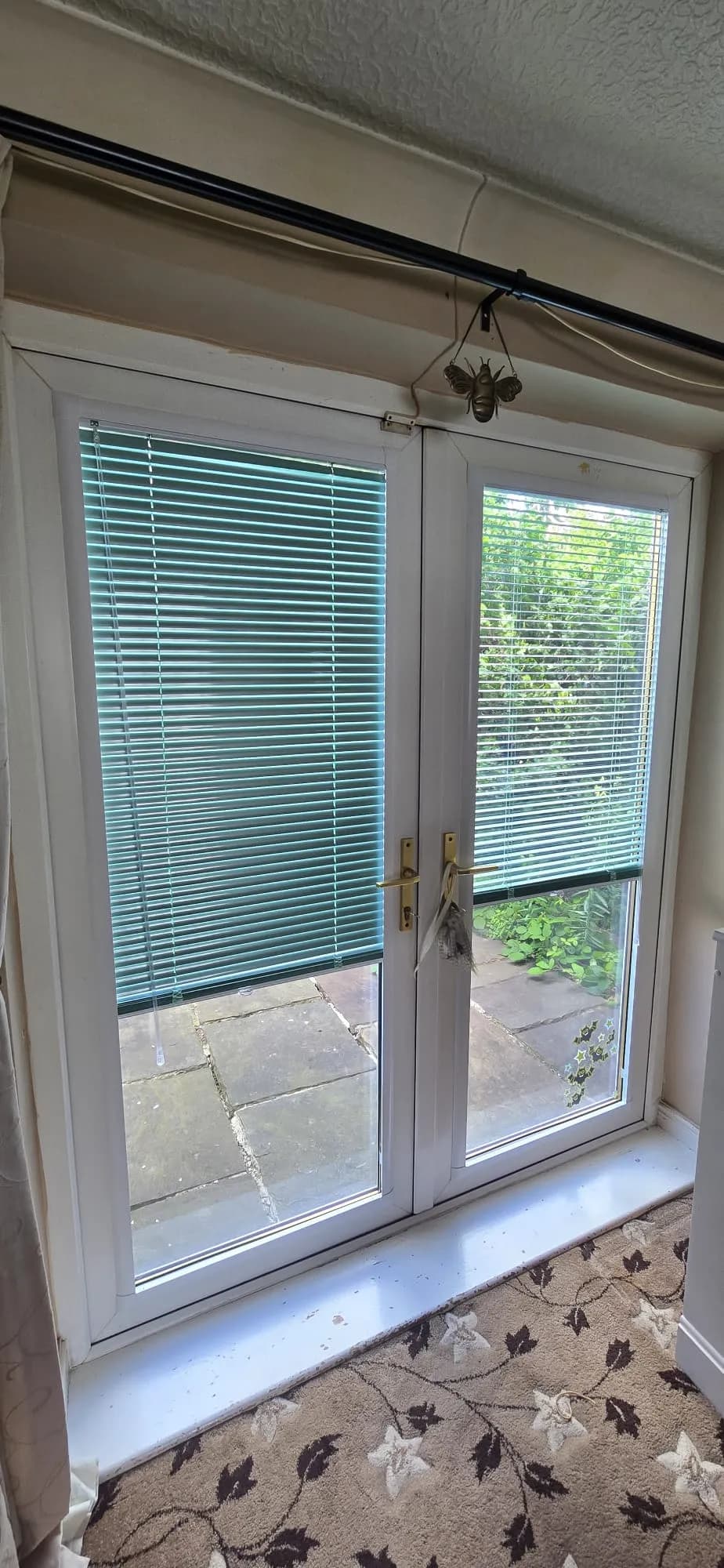 Perfect Fit Venetian blinds on French doors, one raised to reveal the garden