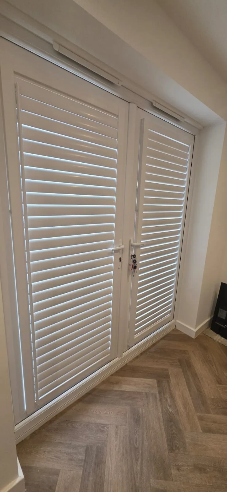 White Perfect Fit plantation shutters fitted to French doors in a hallway