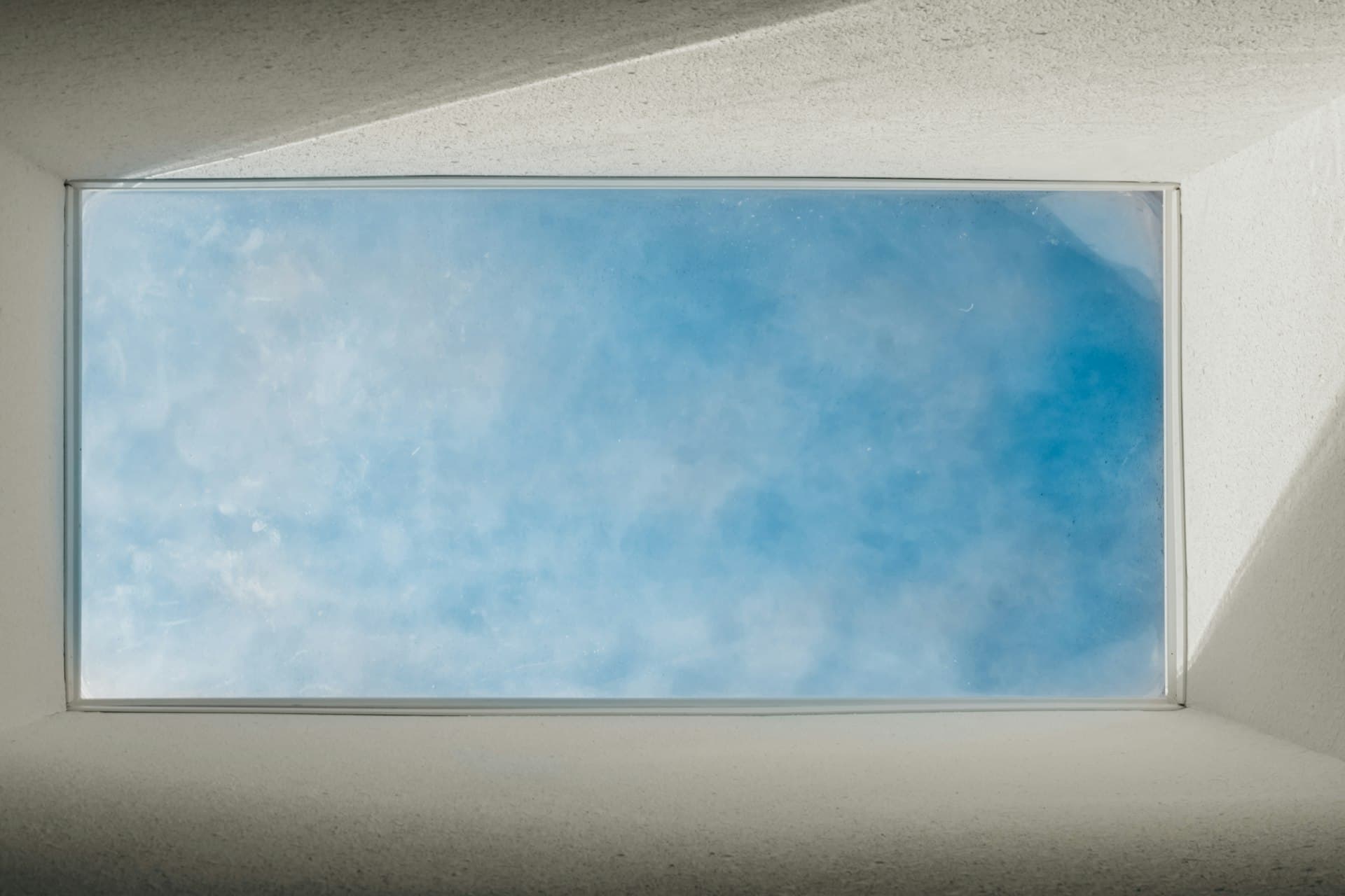 Skylight window looking up at a bright blue sky