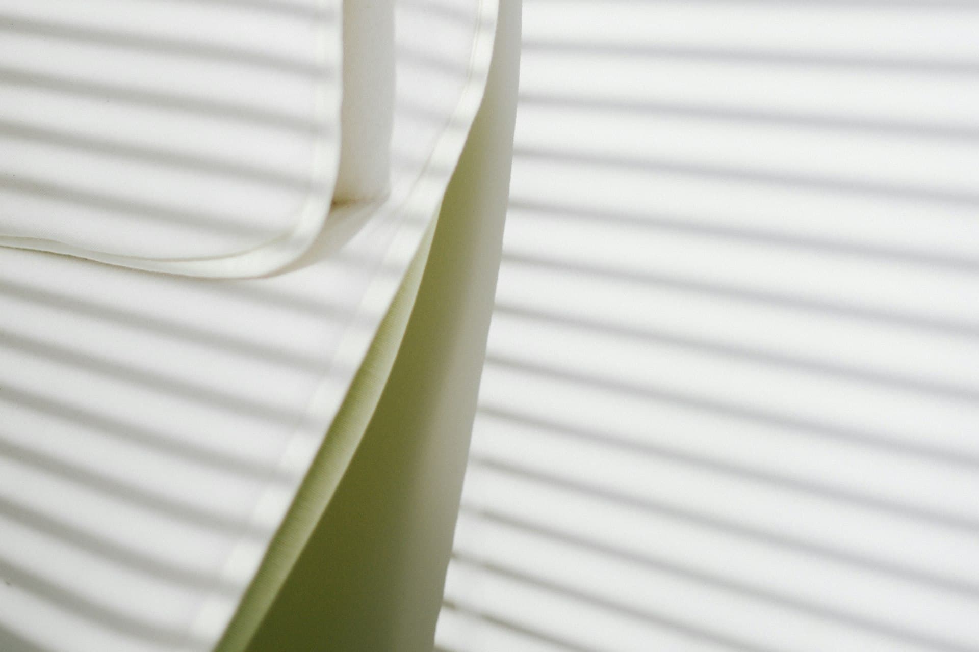 Close-up of soft pleated blind fabric with an armchair