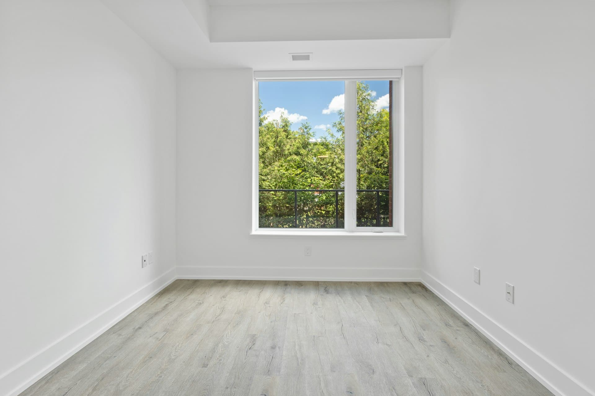 Empty modern bedroom with a large window overlooking greenery