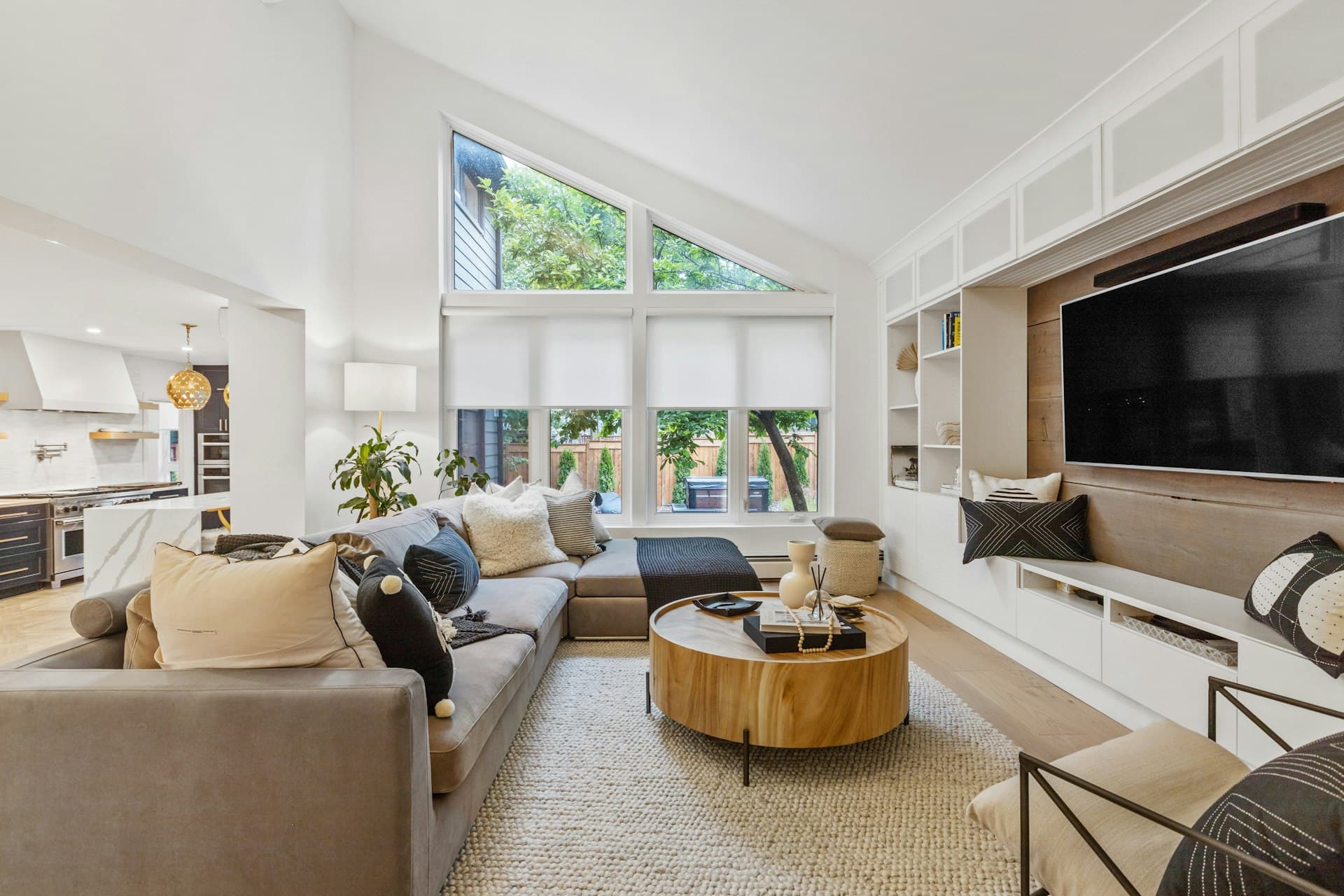 Living room sectional sofa beneath large windows fitted with blinds