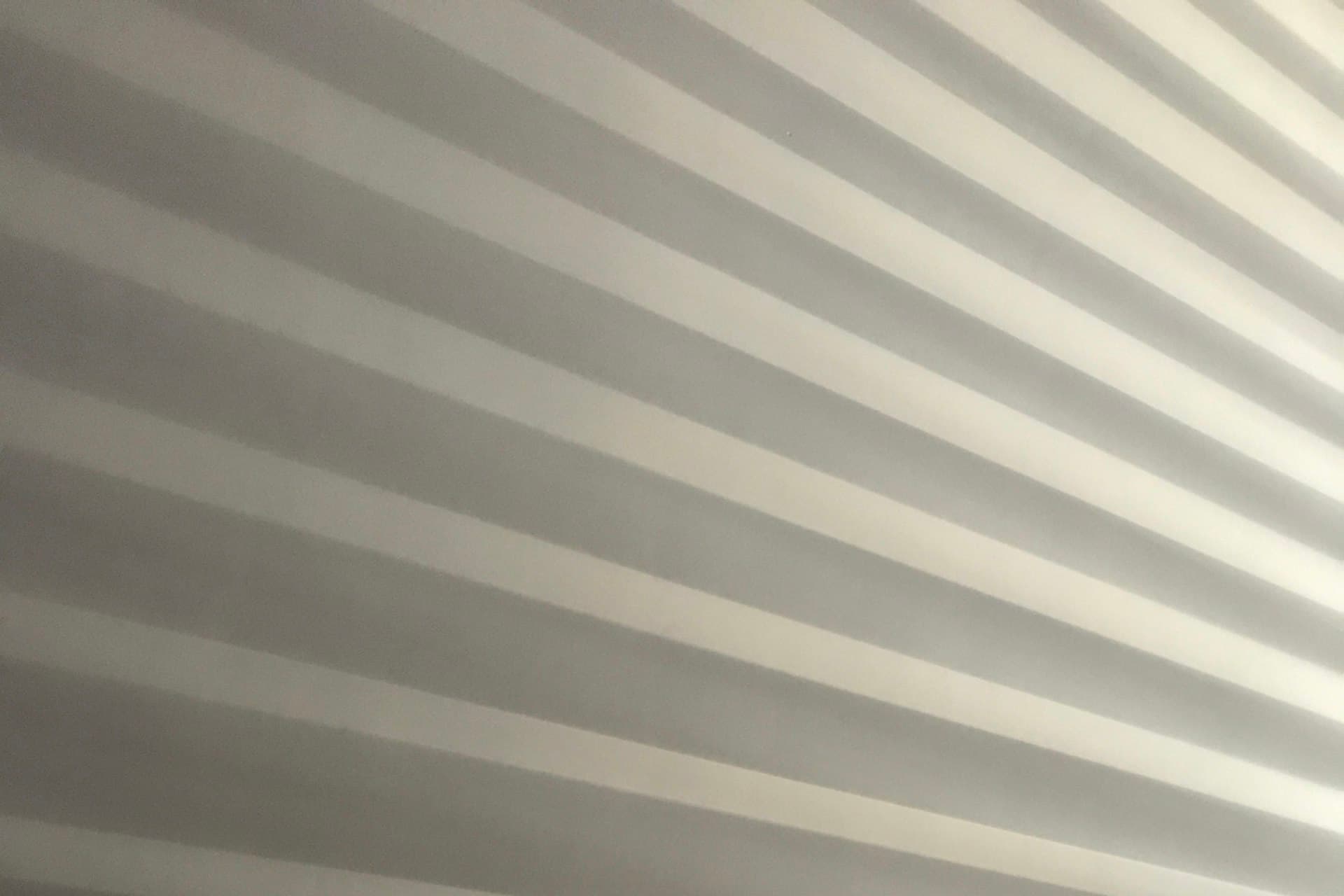 Close-up of grey honeycomb blind fabric with diagonal light